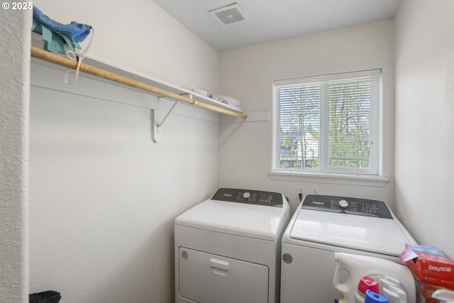 clothes washing area with visible vents, laundry area, and washer and dryer