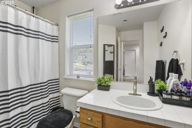 full bath with a textured ceiling, visible vents, curtained shower, vanity, and toilet