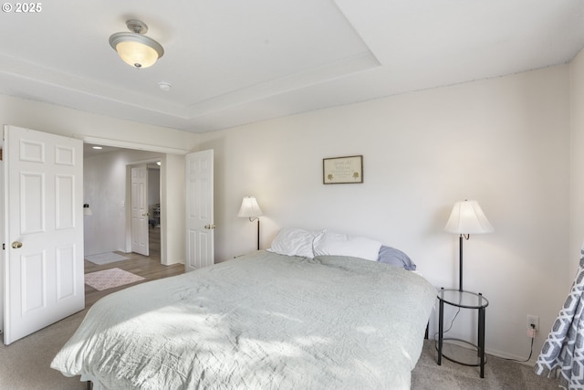 bedroom with carpet floors, baseboards, and a tray ceiling