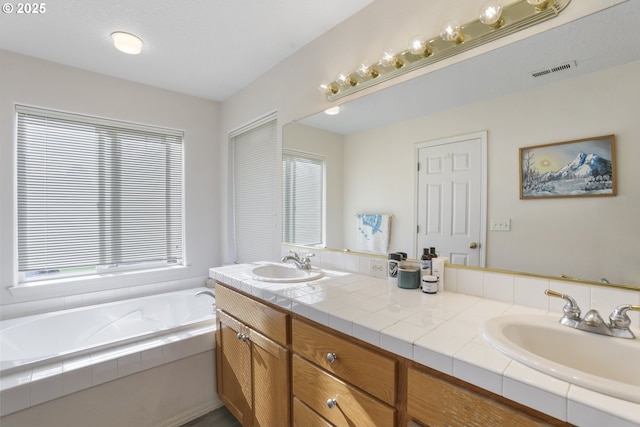 full bathroom with a sink, a garden tub, double vanity, and visible vents