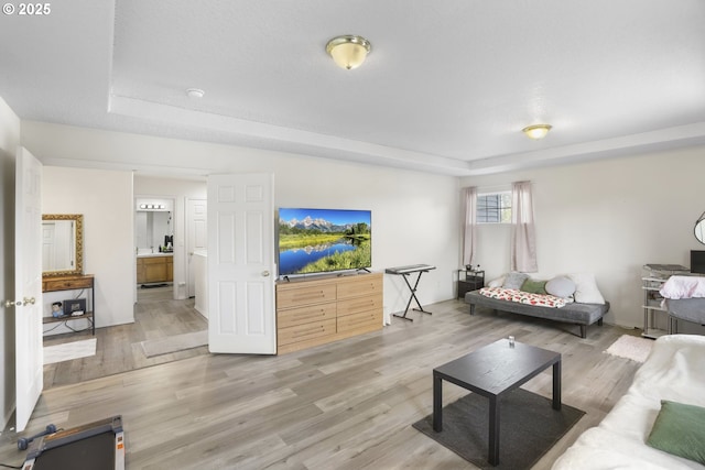 living area featuring a tray ceiling and light wood-style flooring