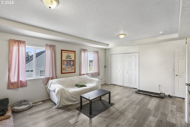 living area featuring a textured ceiling, visible vents, a wealth of natural light, and wood finished floors