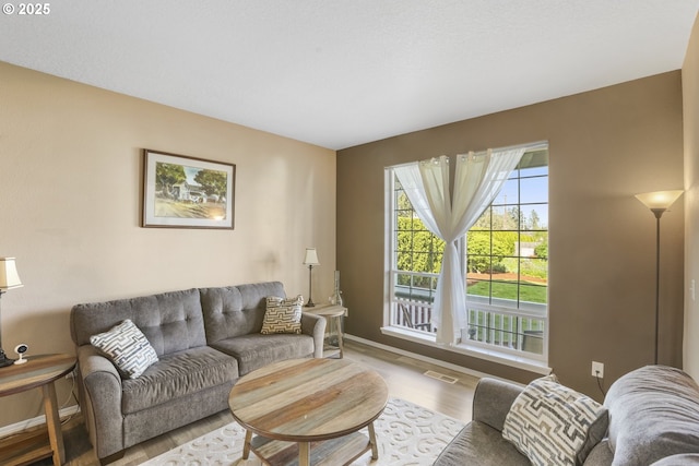 living area featuring baseboards, wood finished floors, and visible vents