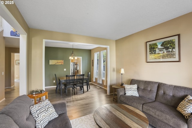 living area with baseboards, an inviting chandelier, and wood finished floors