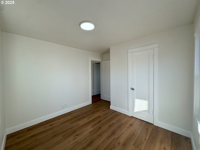 unfurnished bedroom with dark wood-type flooring and baseboards