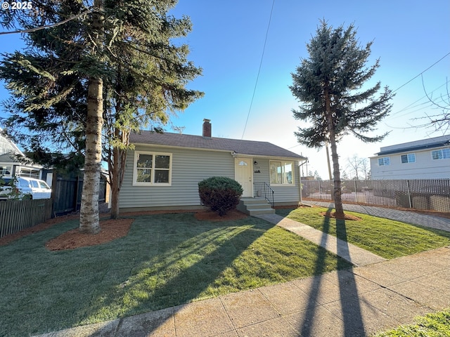 view of front facade with a front yard, fence, and a chimney