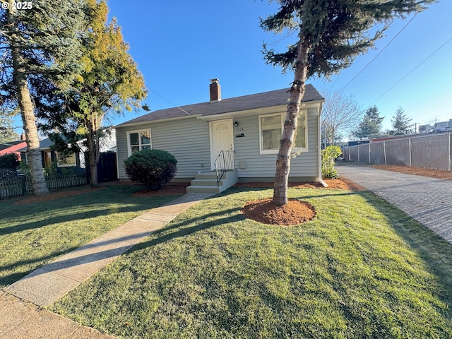 view of front of property featuring a chimney, fence, and a front lawn