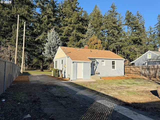 exterior space featuring roof with shingles, a chimney, fence, and a front yard