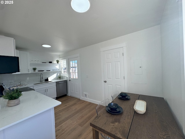 kitchen with white cabinets, wood finished floors, stainless steel dishwasher, open shelves, and a sink