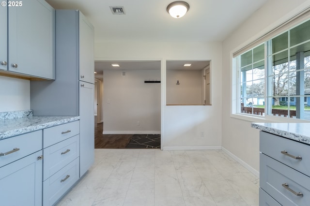 kitchen featuring light stone counters, visible vents, baseboards, and marble finish floor