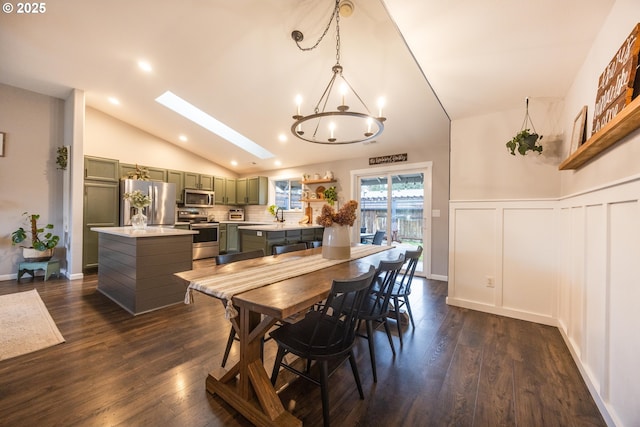 dining area with a chandelier, dark wood-type flooring, a wainscoted wall, and lofted ceiling with skylight