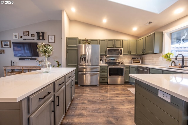 kitchen featuring dark wood finished floors, lofted ceiling, a sink, and appliances with stainless steel finishes