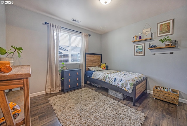 bedroom with visible vents, baseboards, and wood finished floors