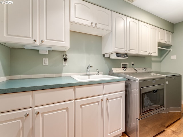 clothes washing area featuring cabinets, separate washer and dryer, sink, and light hardwood / wood-style floors