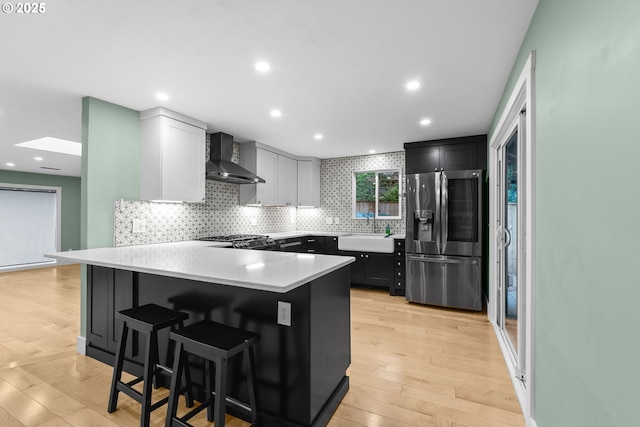 16880 Cortez Ct, Lake Oswego, OR 97035 - kitchen featuring stainless steel fridge, a sink, wall chimney range hood, a peninsula, and backsplash