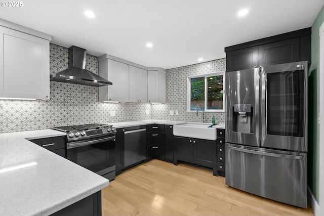 16880 Cortez Ct, Lake Oswego, OR 97035 - kitchen featuring appliances with stainless steel finishes, wall chimney range hood, a sink, light wood-style flooring, and backsplash