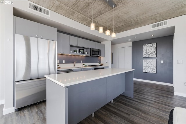 kitchen featuring dark wood finished floors, a kitchen island, baseboards, gray cabinetry, and light countertops