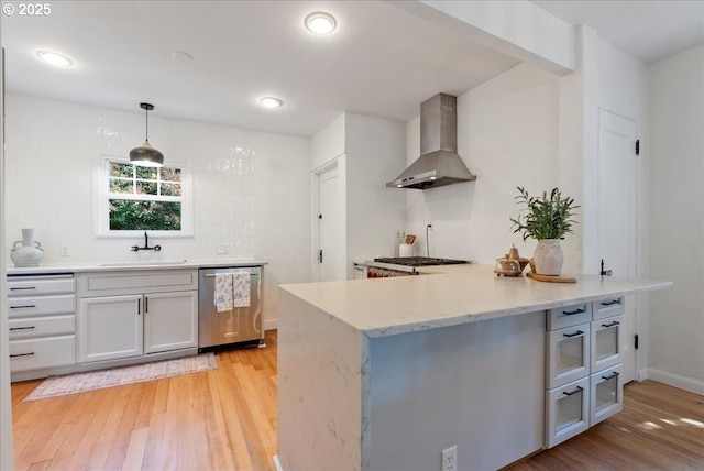 1235 N Farragut St, Portland, OR 97217 - kitchen with wall chimney range hood, stainless steel dishwasher, light wood-style flooring, a peninsula, and light stone countertops