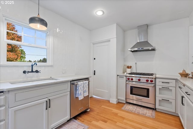 1235 N Farragut St, Portland, OR 97217 - kitchen with appliances with stainless steel finishes, wall chimney exhaust hood, light wood-type flooring, and light countertops