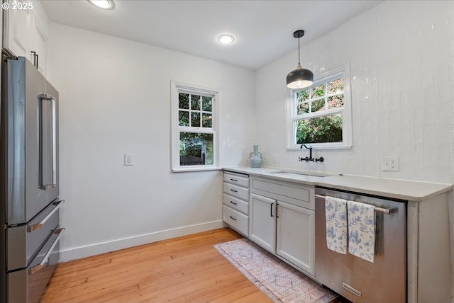 1235 N Farragut St, Portland, OR 97217 - kitchen with appliances with stainless steel finishes, light wood finished floors, light countertops, decorative light fixtures, and white cabinetry