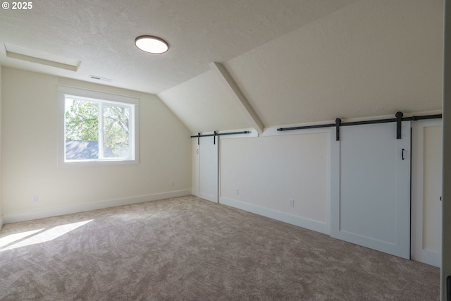 535 E St, Independence, OR 97351 - additional living space featuring carpet, a barn door, vaulted ceiling, and a textured ceiling