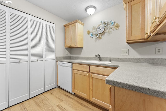 kitchen featuring white dishwasher, sink, light wood-type flooring, a textured ceiling, and light brown cabinetry