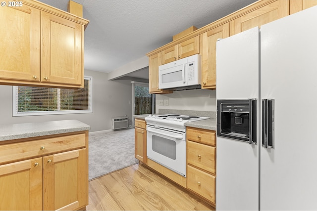 kitchen with light brown cabinets, light wood-type flooring, white appliances, and a wall unit AC