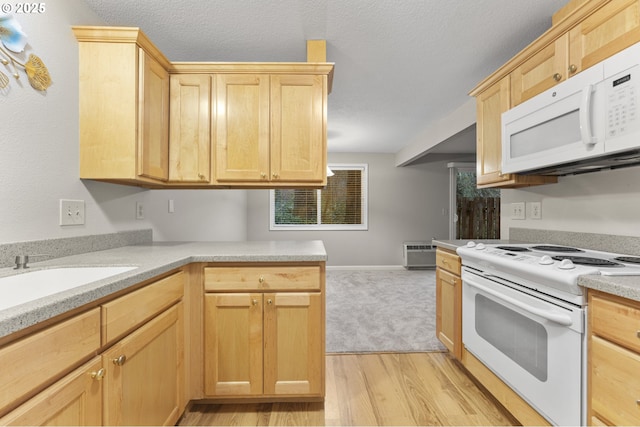 kitchen with light brown cabinetry, white appliances, light hardwood / wood-style flooring, and sink