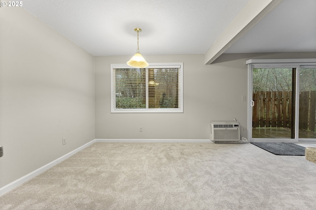 carpeted empty room with beamed ceiling, an AC wall unit, a textured ceiling, and a wealth of natural light