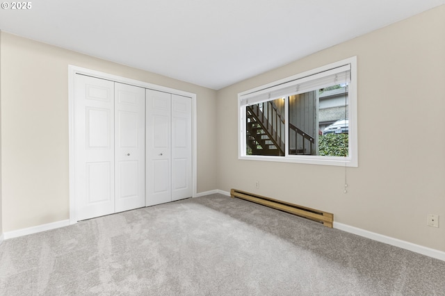 unfurnished bedroom with light carpet, a closet, and a baseboard heating unit