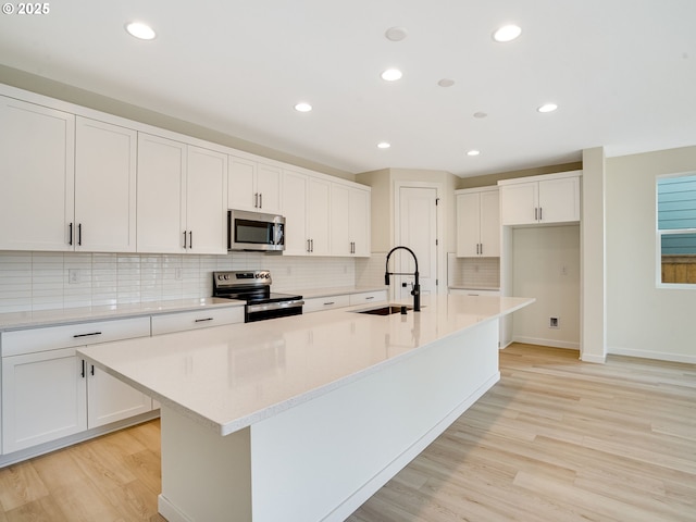 kitchen featuring white cabinetry, appliances with stainless steel finishes, sink, and a center island with sink