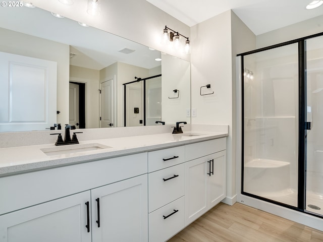 bathroom featuring hardwood / wood-style flooring, vanity, and a shower with shower door