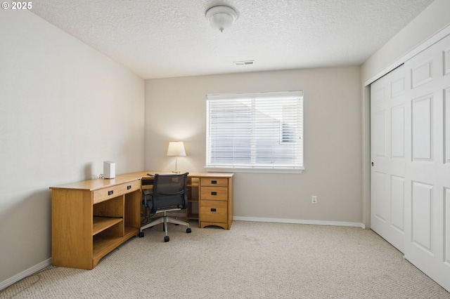office space featuring a textured ceiling, baseboards, and light colored carpet