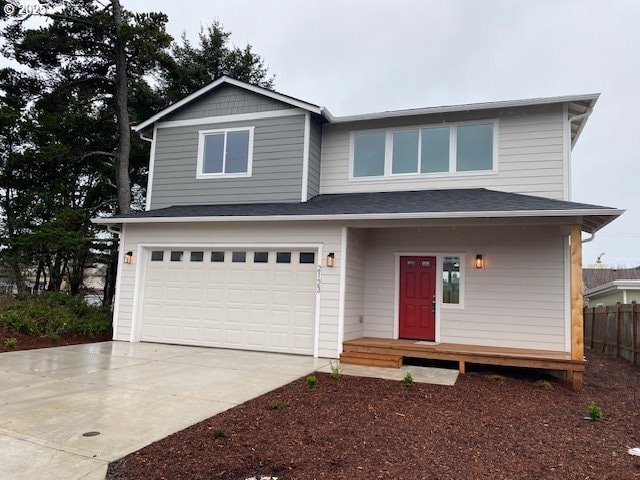 view of front facade with a garage, driveway, and fence