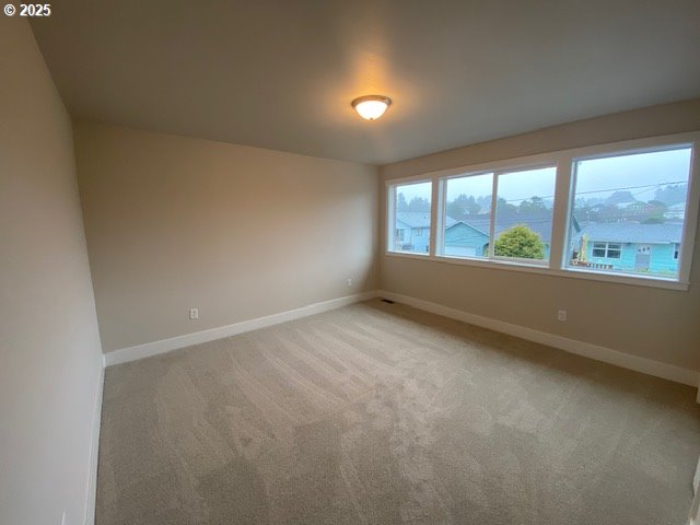 empty room featuring baseboards and light colored carpet