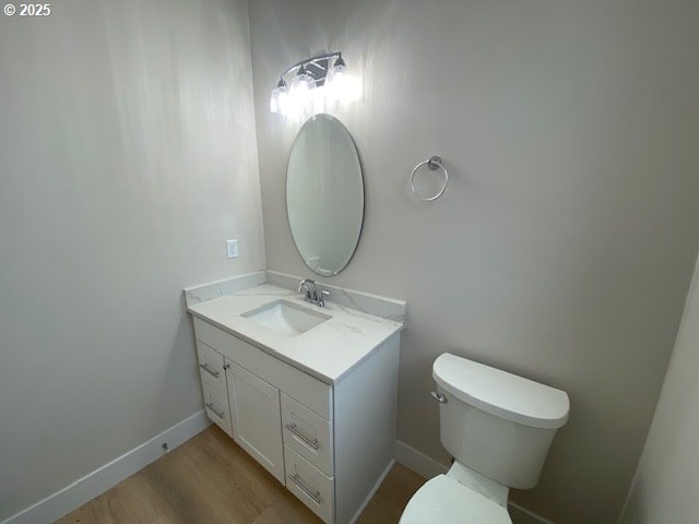 bathroom featuring vanity, toilet, wood finished floors, and baseboards