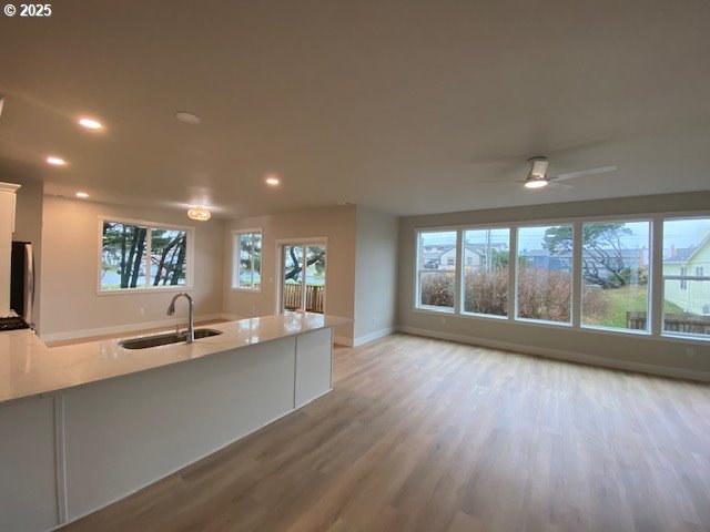 kitchen featuring a sink, light wood finished floors, white cabinets, recessed lighting, and a peninsula