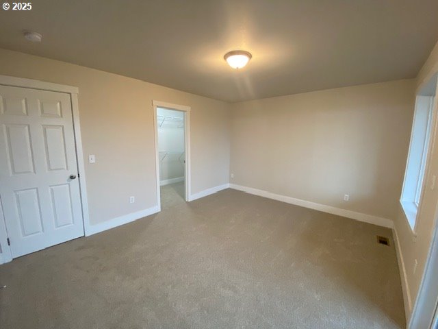unfurnished bedroom with carpet floors, baseboards, a spacious closet, and a closet