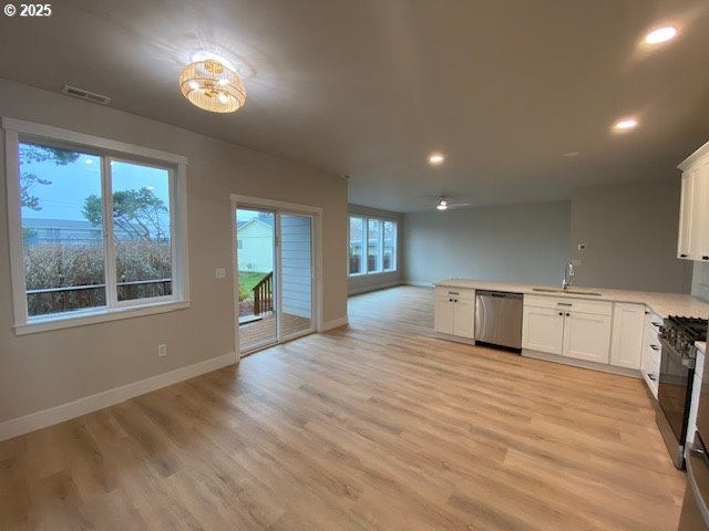 kitchen featuring dishwasher, open floor plan, a sink, a peninsula, and gas stove
