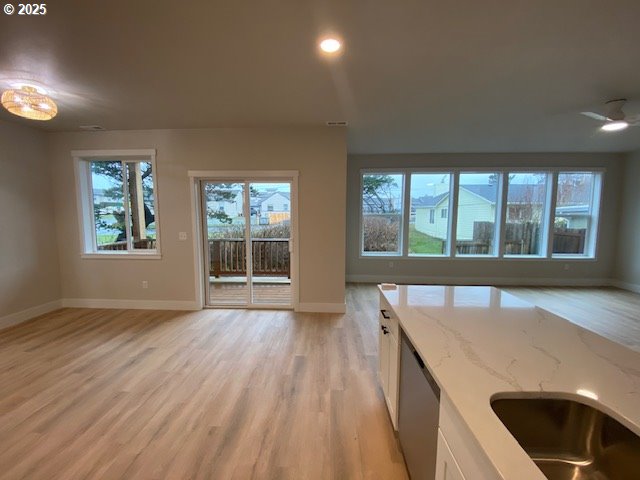 unfurnished living room with light wood-type flooring, baseboards, and recessed lighting