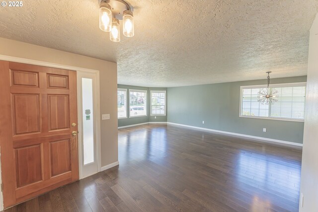 foyer entrance featuring baseboards, a textured ceiling, a chandelier, and dark wood finished floors