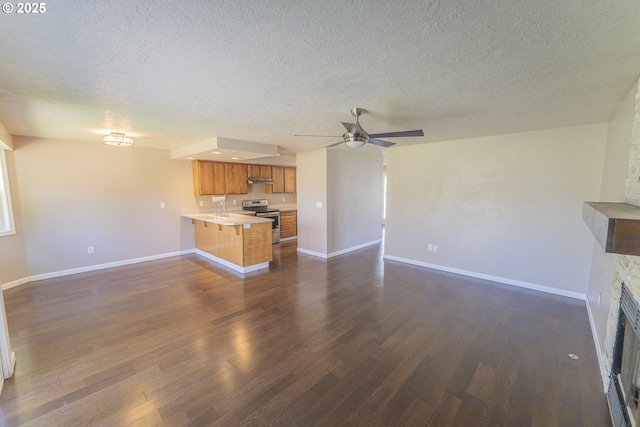 unfurnished living room featuring a textured ceiling, ceiling fan, dark wood-style floors, and baseboards
