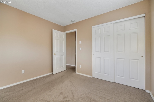 unfurnished bedroom with light colored carpet, a closet, and a textured ceiling