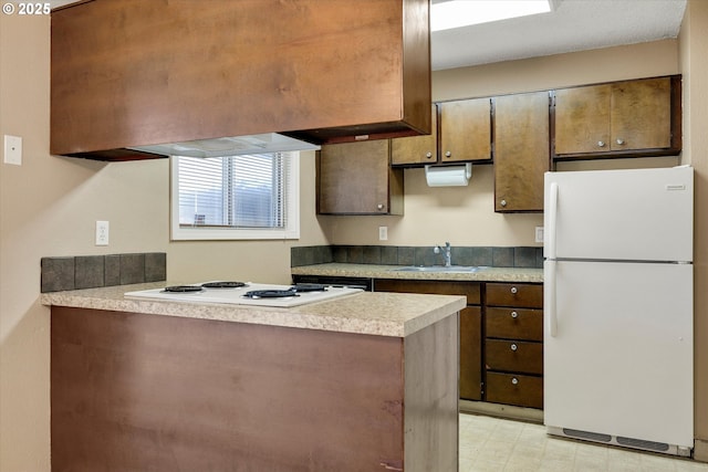 kitchen with white appliances, kitchen peninsula, and sink