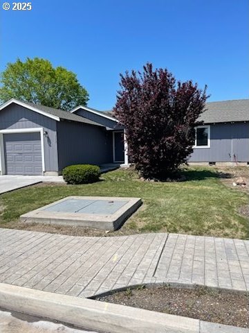 view of front of property with a front yard, concrete driveway, and an attached garage