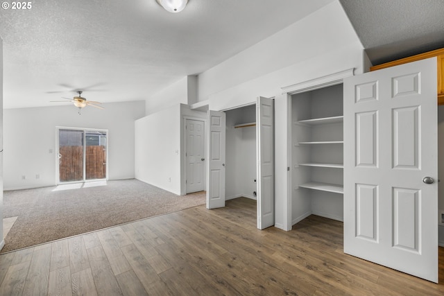 888 SE Kierra Pl, Madras, OR 97741 - unfurnished bedroom featuring baseboards, lofted ceiling, wood finished floors, a textured ceiling, and two closets