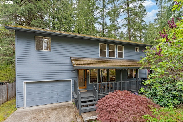 view of front of property with covered porch, fence, driveway, and a garage