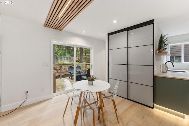 dining space with baseboards, recessed lighting, and light wood-style flooring