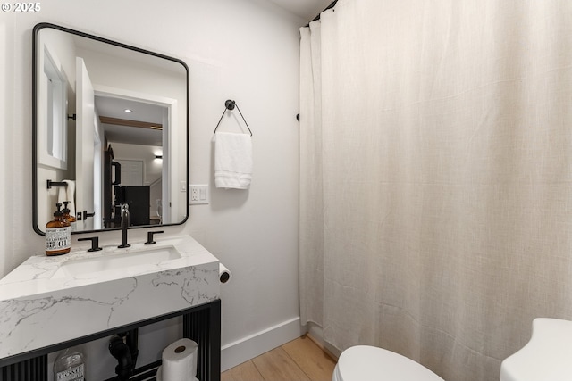 bathroom with vanity, baseboards, toilet, and wood finished floors
