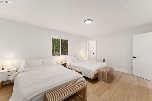 bedroom featuring baseboards and light wood finished floors